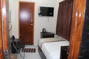a small bedroom with a bed and a television at Hotel GVP Residency in Tirupati