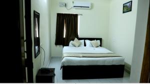a bedroom with a bed with white sheets and a window at Hotel GVP Residency in Tirupati