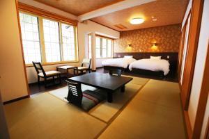 野沢温泉村にある中島屋旅館のベッド2台、テーブルと椅子が備わるホテルルームです。