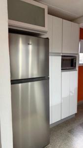 a stainless steel refrigerator in a kitchen with white cabinets at Hostel All inclusive in Zárate