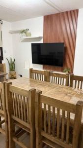 a dining room with a wooden table and a flat screen tv at Hostel All inclusive in Zárate