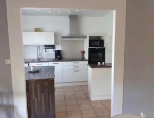 a kitchen with white cabinets and black appliances at Maison Treize vents in Treize-Vents