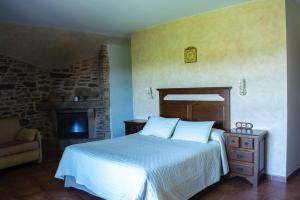 a bedroom with a bed and a stone fireplace at Casa rural osvilares in Santiago de Compostela +74 photos