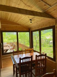 a dining room with a table and chairs and windows at Bujtina Pllumi Theth in Theth +70 photos