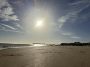 a beach with a pier and the sun in the sky at South Beach B & B in Lowestoft