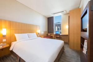 a hotel room with a large white bed and a window at Ibis Ambassador Busan City Centre in Busan