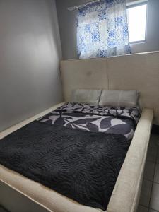 a bed with a black and white comforter and a window at Private Room in a 2-Bed Apartment Shared in Farmall