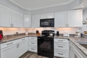 a kitchen with white cabinets and a black stove top oven at 4104 - Sever's Hideaway in Duck +29 photos