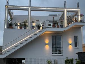 a white house with a staircase with lights on it at Aura boutique hotel in Vlorë