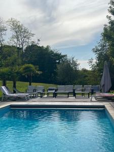 a swimming pool with a bench and chairs next to it at La maison de Blandine in Honfleur
