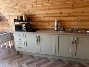 a kitchen with white cabinets and a counter with a sink at Milldown Glamping in Coldingham +12 photos