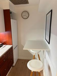 a kitchen with a table and two stools and a clock at Lille Skovgaarden ved parken med gratis parkering in Randers