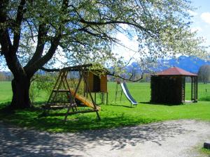 ein Spielplatz mit Rutsche und Baum in der Unterkunft Alluring Holiday Home in Ubersee with Whirlpool in Übersee