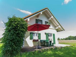 ein Haus mit einem roten Regenschirm und einer Bank in der Unterkunft Alluring Holiday Home in Ubersee with Whirlpool in Übersee
