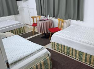a room with three beds and a table and chairs at Rooms Đenadija in Hrvatska Kostajnica