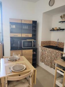 a dining room with a table and a microwave at Le cocon de Suze in Suze-la-Rousse