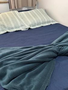 a bed with a green blanket on it at Hospedagem Aconchego in Lagoa Santa