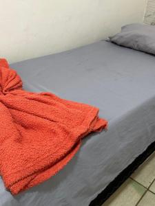 a red blanket laying on top of a bed at Hospedagem Aconchego in Lagoa Santa