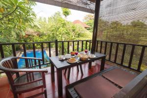 una mesa y una silla en un balcón con comida. en Tropical Bali Hotel, en Sanur
