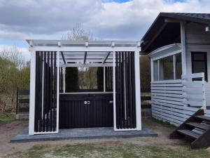 a white shed with a gate and a building at Domek na Roztoczu - Jacuzzi in Krasnobród