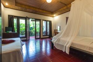 a bedroom with two beds with a mosquito net at Tropical Bali Hotel in Sanur