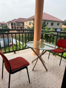 a glass table and two chairs on a balcony at Afranasa Inn in Tema