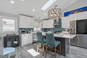 a kitchen with white cabinets and green chairs at Point Judith Coastal Retreat in Narragansett