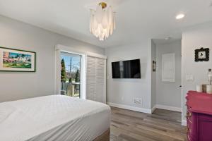 a bedroom with a bed and a tv and a chandelier at Point Judith Coastal Retreat in Narragansett