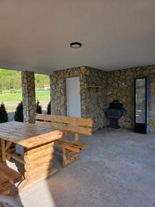 a wooden picnic table in a room with a stone wall at Villa Sanja I Villa Aleksa in Bratunac