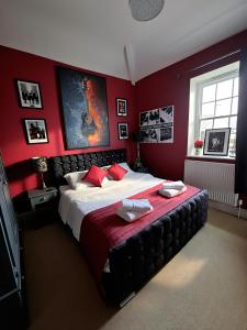 a bedroom with a large bed with red walls at The Old Court House & Jail in Menai Bridge