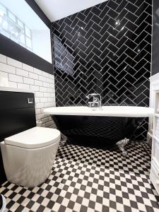 a black and white bathroom with a tub and a toilet at The Old Court House & Jail in Menai Bridge +39 photos