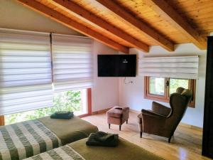 a bedroom with two beds and a chair and a television at RINCON DE MUTILOA Balcón del Aitzgorri HabTuristica in Mutiloa