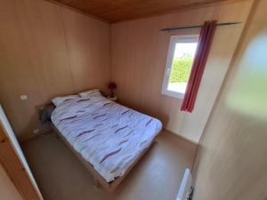 a small bed in a small room with a window at Chalets au bord du lac de Lavalette in Lapte