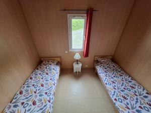 a small room with two beds and a window at Chalets au bord du lac de Lavalette in Lapte