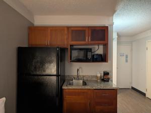 a kitchen with a black refrigerator and a sink at Home Place Suites in Bartlesville