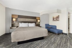a hotel room with a bed and a blue chair at Best Western Plus Wausau Tower Inn in Wausau +52 photos
