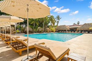 a pool with chairs and umbrellas next to a resort at Sonesta Hotels & Resorts Livingstone Curacao in Willemstad