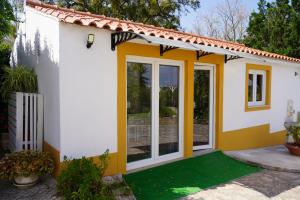 a small house with yellow doors and a yard at Estudio Robusto in Monte do Valão