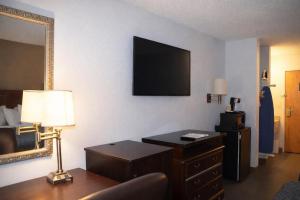 a hotel room with a desk and a television on the wall at Americas Best Value Inn Raleigh in Raleigh