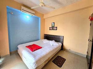 a bedroom with a white bed with a red pillow on it at Epindi Studio Apartment in Cox's Bazar