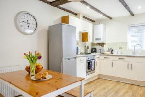 a kitchen with a wooden table and a clock on the wall at 2 Bed in Shanklin oc-c36037 in Shanklin +22 photos