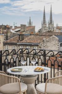 a table and chairs with a plate of pizza on a balcony at Hôtel Singulier Bordeaux - Boutique Hôtel & Spa Anne Semonin in Bordeaux
