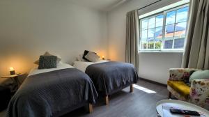 a bedroom with two beds and a window and a chair at Cimo das Dutras in Horta