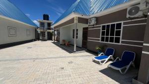 two blue chairs sitting on a patio next to a building at ES Apartments in Dodoma