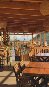 a restaurant with wooden tables and chairs on a deck at Karos Hotel Llaman in Himare