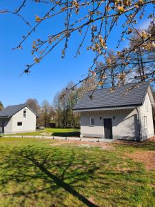 a white barn with a black roof at Mia Domo - wypoczynek w Górach Suchych, Kamiennych i Sowich in Głuszyca