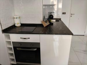 a kitchen with white cabinets and a black counter top at Apartamentos Dali 1 in Guadix +7 photos