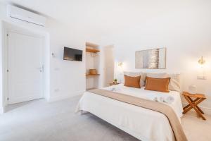 a white bedroom with a large bed and a tv at Enea Dimora Procida in Procida