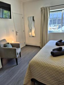 a bedroom with a bed and a chair and a window at Cimo das Dutras in Horta +30 photos
