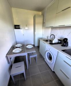 a small kitchen with a table and a washing machine at Cimo das Dutras in Horta